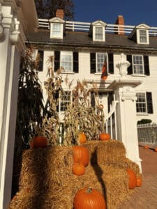 Harvest decorations with pumpkins, hay bales, and dried cornstalks arranged at the entrance of the historic Ropes Mansion in Salem, Massachusetts.