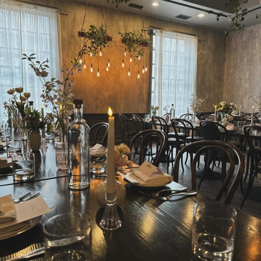 A beautifully arranged dining room at Ledger Restaurant in Salem, Massachusetts, showcasing elegant table settings with candlelight, fresh floral arrangements, and modern decor in a warm, inviting atmosphere.
