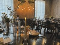 A beautifully arranged dining room at Ledger Restaurant in Salem, Massachusetts, showcasing elegant table settings with candlelight, fresh floral arrangements, and modern decor in a warm, inviting atmosphere.