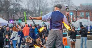 A performer in Salem Massachusetts juggling flaming torches as a captivated crowd enjoys the festivities at the Frozen Fire Festival.