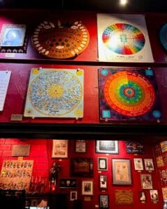 A collection of unique circular spirit boards and intricate destiny wheels on display at the Salem Witch Board Museum, each featuring vibrant colors, symbols, and text.
