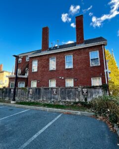 The back of the Nathaniel H. Felt House in Salem, Massachusetts, featuring a red brick facade, tall chimneys, and a wooden fence enclosing the yard.
