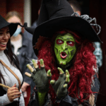 Borah, a costumed witch with green face paint and red hair, captivates visitors in Salem, Massachusetts, with her animated expressions and elaborate attire.