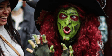 Borah, a costumed witch with green face paint and red hair, captivates visitors in Salem, Massachusetts, with her animated expressions and elaborate attire.