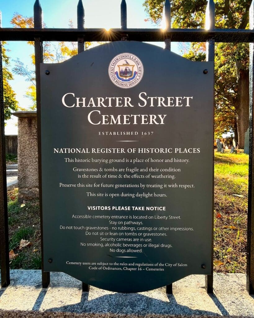 A historical marker at the entrance of the Charter Street Cemetery in Salem Massachusetts, established in 1637, detailing its inclusion in the National Register of Historic Places and providing visitor guidelines.