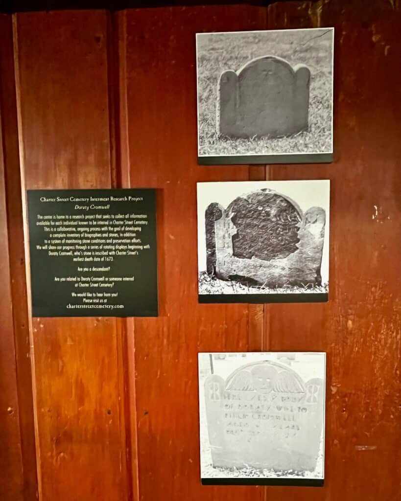 Charter Street Cemetery display at the historic Pickman House in Salem, Massachusetts, featuring photos of gravestones and a sign about Dorothy Cromwell's interment and the cemetery research project.