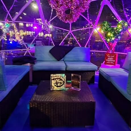  Inside a glowing dome at the Salem Massachusetts Frozen Fire Festival, soft blue seating surrounds a low table, accented by sparkling heart-shaped decor and twinkling lights.