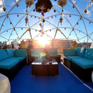 A cozy igloo-style dome in Salem Massachusetts, decorated with hanging ornaments, bathed in sunlight during the Frozen Fire Festival.