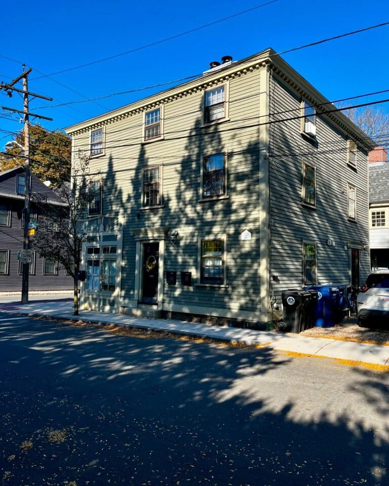 David Ropes House in Salem, Massachusetts, a three-story green wooden building with historical significance, set against a sunny blue sky.