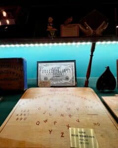 A showcase of rare spirit communication boards, including the Telepah Communication Board and Witchery Board, at the Salem Witch Board Museum in Salem, Massachusetts.
