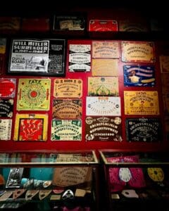 A wall filled with vintage Ouija boards at the Salem Witch Board Museum in Salem, Massachusetts, showcasing various designs, colors, and styles from different time periods.