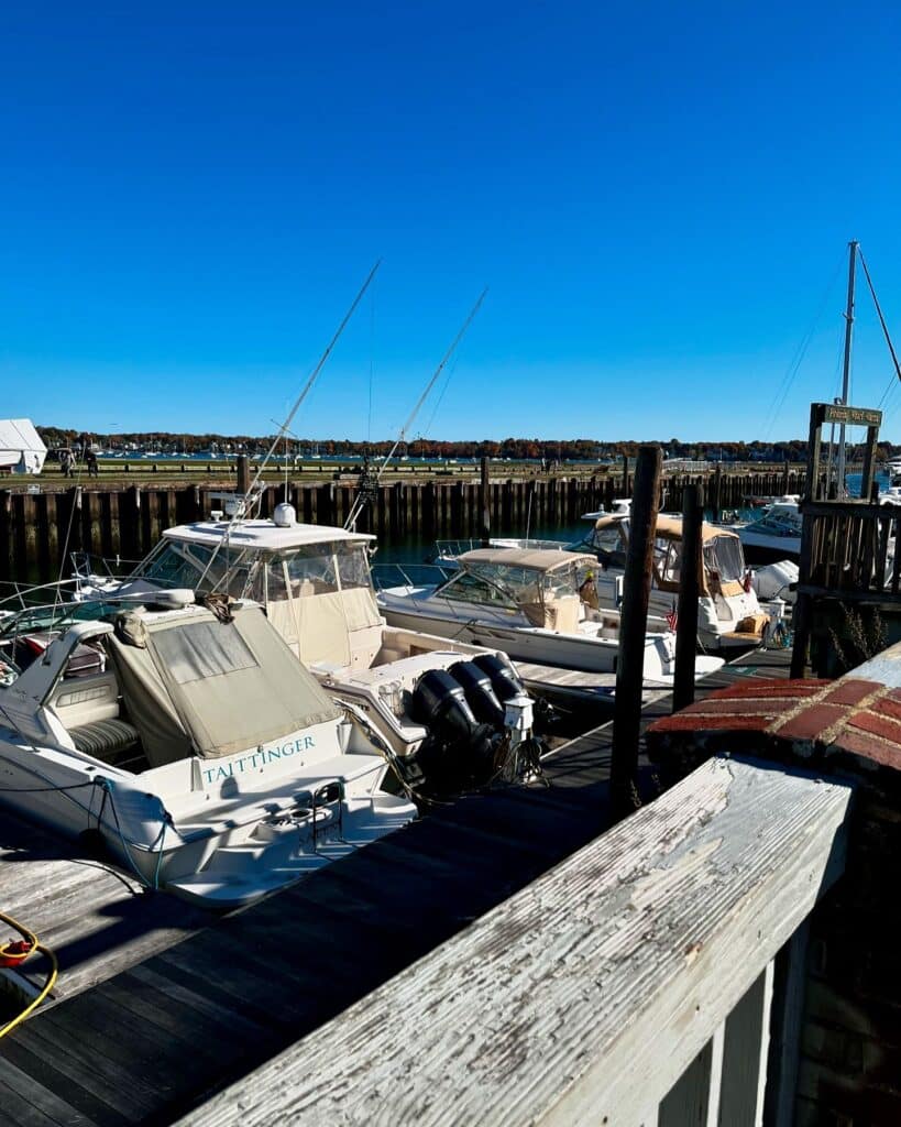Boats moored at Salem Harbor in Salem, Massachusetts, with a clear blue sky and wooden docks surrounded by calm waters.