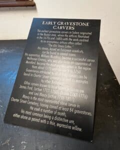 Informational plaque about early gravestone carvers in Salem, Massachusetts, highlighting their contributions to Charter Street Cemetery and gravestone motifs.