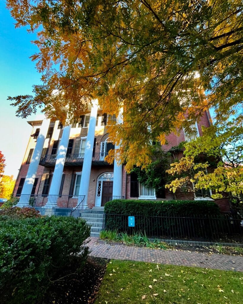 The Andrew-Safford House surrounded by vibrant autumn leaves in Salem Massachusetts, showcasing Federal-style architecture with grand columns and a brick façade.