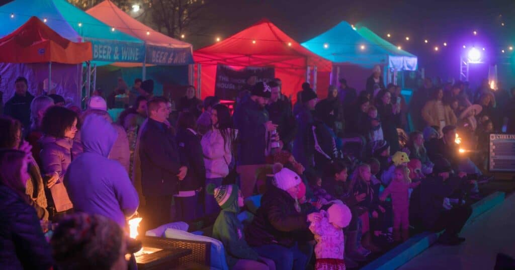  Festival attendees gather under colorful tent lighting at the Frozen Fire Festival in Salem, Massachusetts, enjoying the warm ambiance and live entertainment.