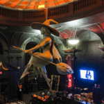 Inside Blackcraft Salem in Salem, Massachusetts, featuring a suspended witch sculpture riding a broom under an orange-lit dome ceiling, surrounded by gothic decor and merchandise displays.