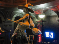 Inside Blackcraft Salem in Salem, Massachusetts, featuring a suspended witch sculpture riding a broom under an orange-lit dome ceiling, surrounded by gothic decor and merchandise displays.