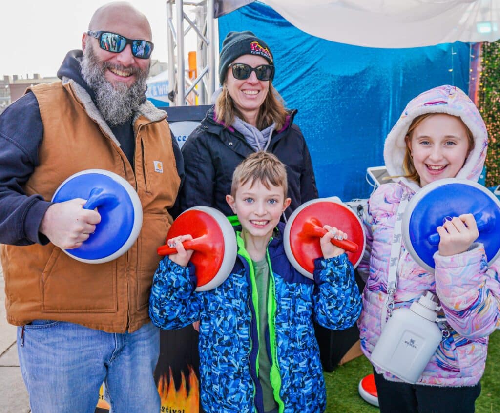  A family in Salem Massachusetts posing with colorful curling stones, smiling and enjoying activities at the Frozen Fire Festival.