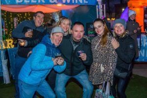 A group of friends enjoying drinks and posing for a fun photo at the Beer & Wine tent during the Salem Frozen Fire Festival in Salem Massachusetts.