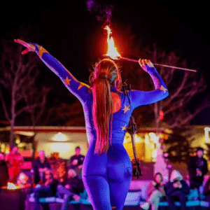 A fire performer in Salem Massachusetts, wearing a vibrant blue costume adorned with yellow stars, wows the audience at the Frozen Fire Festival.