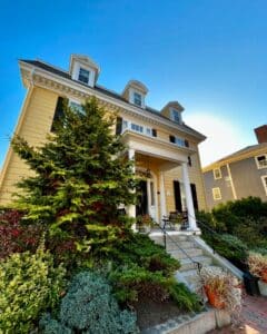 Front porch and entryway of the John P. Peabody House in Salem Massachusetts, featuring white columns, decorative greenery, and a welcoming staircase leading to the entrance.