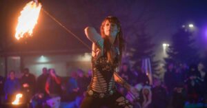 A fire performer spins a flaming staff with confidence and elegance at the Frozen Fire Festival in Salem, Massachusetts, captivating the crowd with her skill and focus.