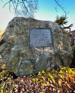 A granite stone memorial with a plaque commemorating the Twenty Third Regiment in Salem, Massachusetts, surrounded by autumn leaves.