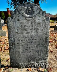Gravestone of Elisabeth Herbert in Salem Massachusetts's Old Burying Point cemetery, featuring a carved angel at the top, intricate floral details, and an inscription honoring her as a devoted wife and mother, who passed in 1772 at age 55.