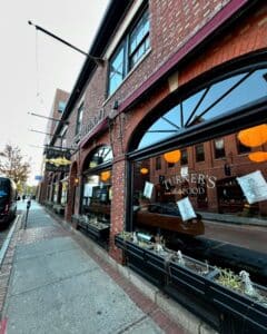 A sidewalk view of Turner's Seafood restaurant in Salem, Massachusetts, featuring the iconic brick exterior, arched windows with reflections of the street, and decorative planters.
