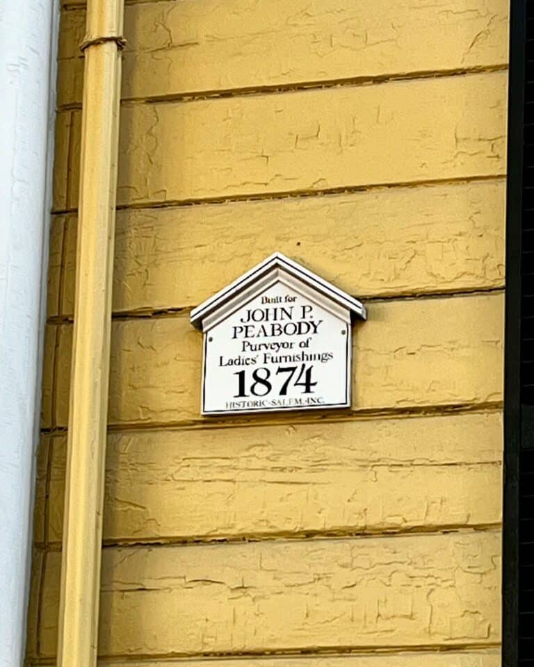 Plaque marking the John P. Peabody House in Salem Massachusetts, highlighting its construction in 1874 and its historical significance as a purveyor of ladies' furnishings.