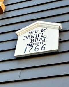 A white wooden plaque on the exterior of the Daniel Bray House in Salem, Massachusetts, marked with "Built by Daniel Bray, Mariner 1766," emphasizing its historic roots.