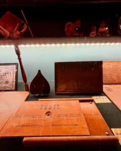 A detailed view of antique Ouija boards and talking boards displayed at the Salem Witch Board Museum in Salem, Massachusetts, highlighting "The Witches' Fortune Teller" by Milton Bradley Co.
