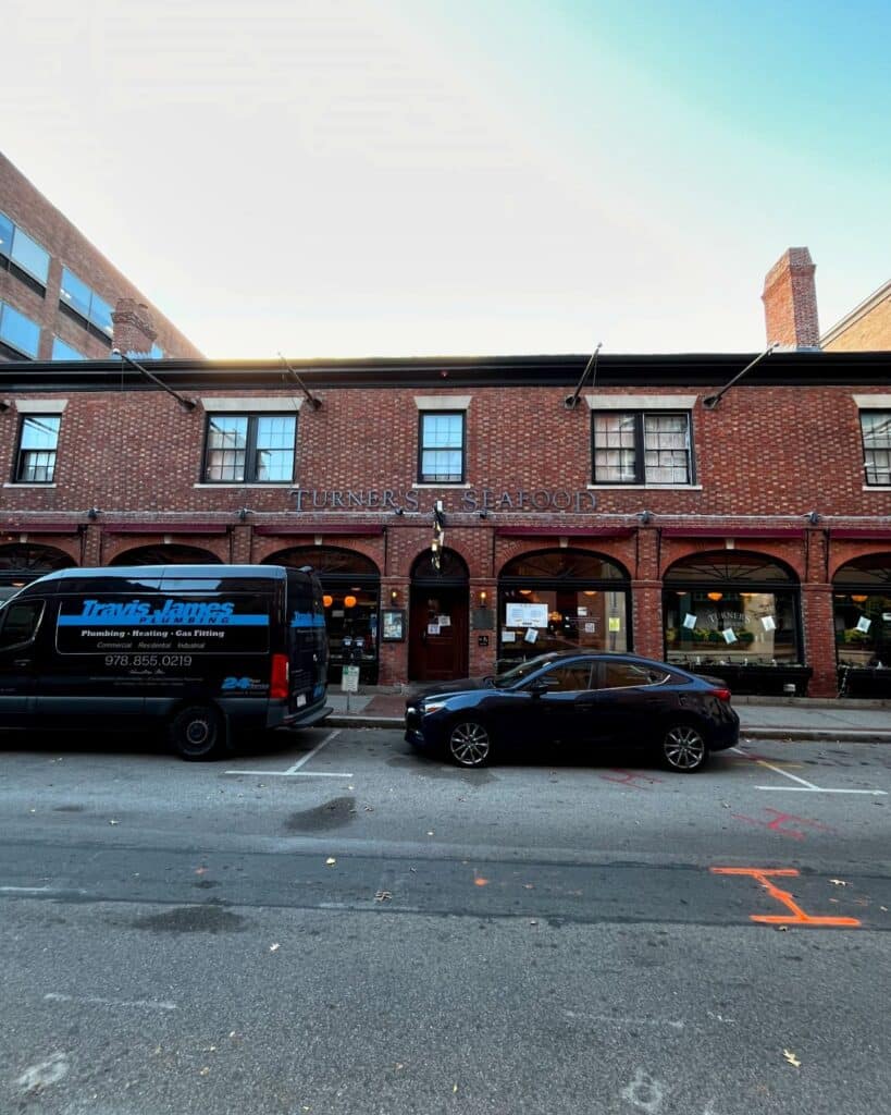 Front facade of Turner's Seafood building in Salem Massachusetts, featuring brick architecture, arched windows, and parked vehicles on the street.