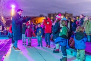 A lively group of children engaging in a fun activity led by a host during the Salem Frozen Fire Festival in Salem Massachusetts, with a colorful evening backdrop.