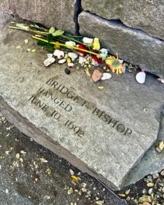 A memorial stone at the Salem Witch Trials Memorial in Salem, Massachusetts, commemorating Bridget Bishop, engraved with her name and the date of her execution, June 10, 1692. Flowers and small items are left on the stone in tribute.