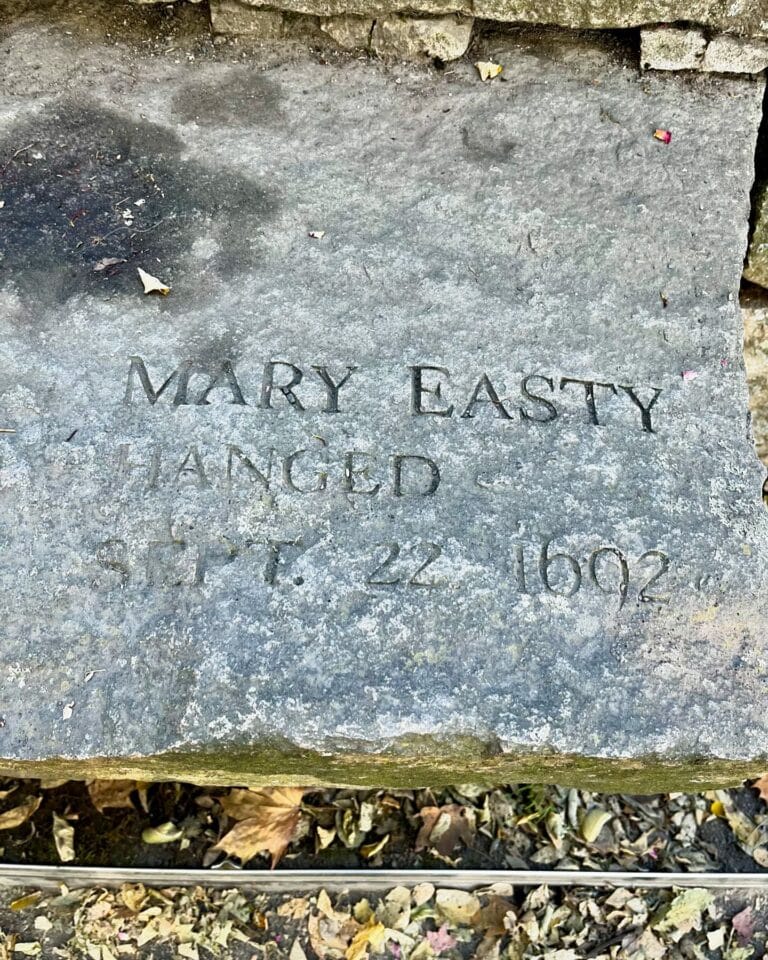 A memorial stone at the Salem Witch Trials Memorial in Salem, Massachusetts, honoring Mary Easty, engraved with her name and the date of her execution, September 22, 1692. Fallen leaves surround the stone.