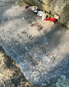 A memorial stone at the Salem Witch Trials Memorial in Salem, Massachusetts, honoring Mary Parker, engraved with her name and the date of her execution, September 22, 1692. Flowers and seashells are placed as tributes.