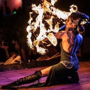 A fire dancer in Salem Massachusetts performing with intricate props, surrounded by flames during the Frozen Fire Festival.