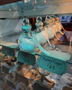 Glass bottles labeled "Mummy Finger" and "Yeti" sit on a shelf in a shop in Salem, Massachusetts, filled with cotton and wrapped in twine.