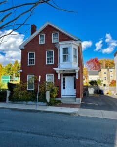 The Nathaniel H. Felt House in Salem, Massachusetts, a historic red brick building with a white bay window, granite steps, and a small garden enclosed by an iron fence.