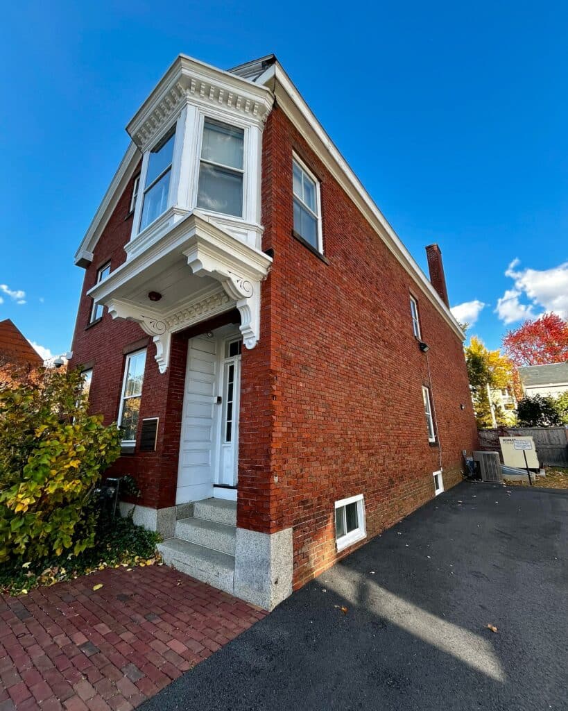 The Nathaniel H. Felt House in Salem, Massachusetts, a red brick historic building with a large white bay window, ornate brackets, and granite steps leading to the entrance.