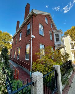 The Nathaniel H. Felt House in Salem, Massachusetts, a red brick historic building with a white bay window, black iron fence, and a ramp leading to the entrance.