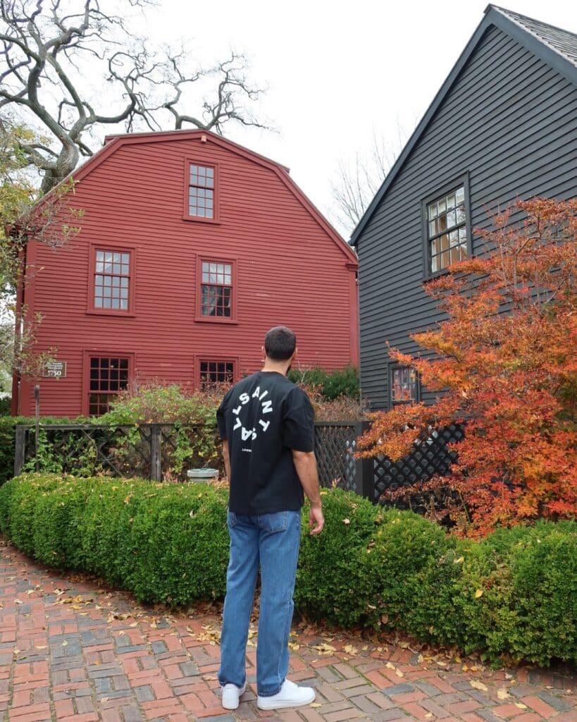 Nathaniel Hawthorne's Birthplace in Salem Massachusetts a red colonial house with a person standing on a brick path near green hedges and autumn leaves.