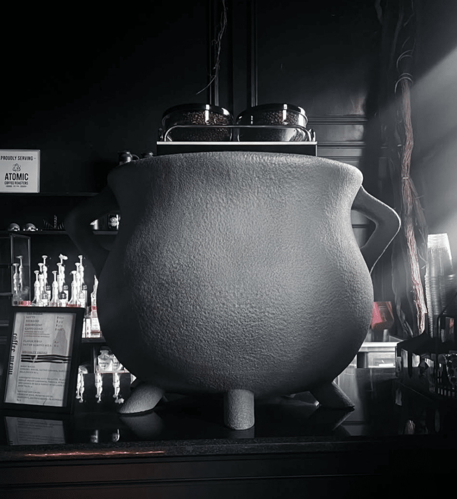  A large, textured cauldron displayed on the cafe counter at Blackcraft Salem in Salem, Massachusetts, surrounded by coffee equipment and gothic decor.