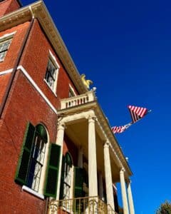 Angled view of the Salem Custom House in Salem, Massachusetts, highlighting its Federal-style columns, green shutters, and the golden eagle under a vivid blue sky.