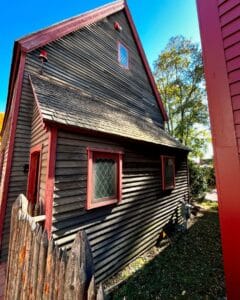 Side view of a historic wooden house with red trim and picket fence in Salem Massachusetts, near the Salem Witch Trials Memorial.