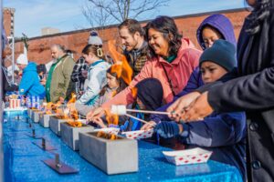 Families in Salem Massachusetts gathered around small fire pits, toasting marshmallows and enjoying sweet treats at the Frozen Fire Festival.