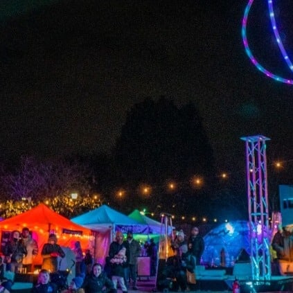 Visitors at the Salem Massachusetts Frozen Fire Festival gathering under illuminated tents and decorative lights, enjoying the festive winter atmosphere.