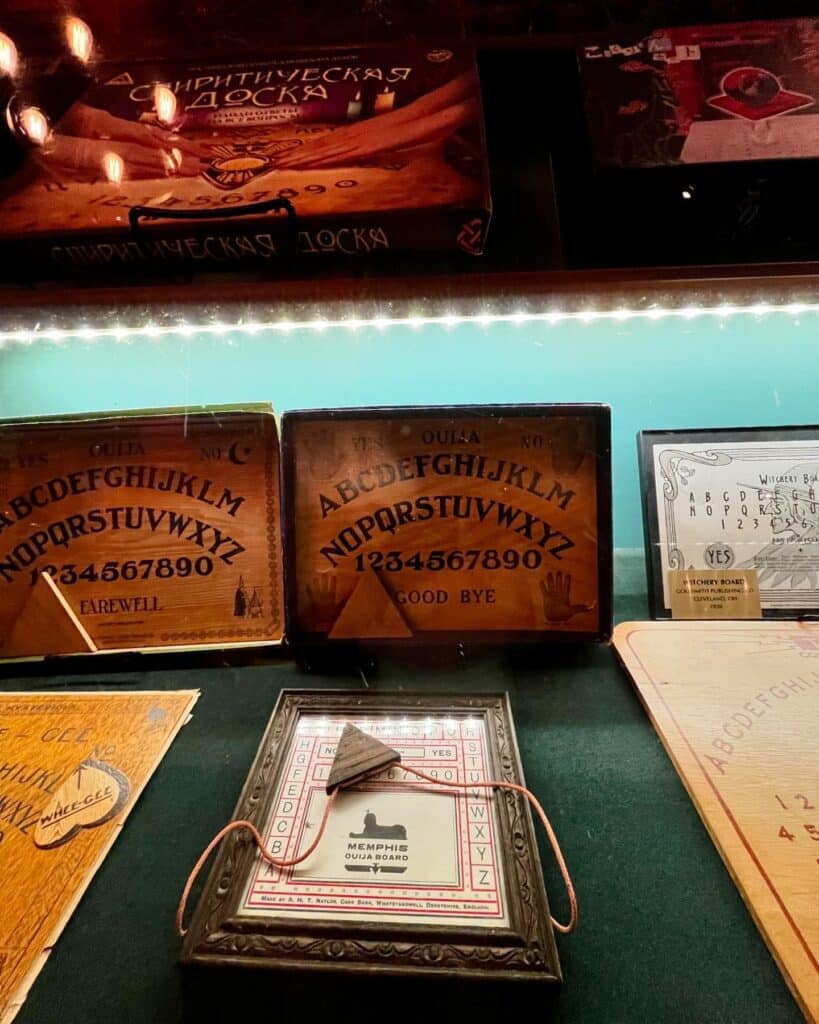 A showcase of vintage Ouija boards, including a Memphis Ouija board and international spirit communication artifacts, at the Salem Witch Board Museum in Salem, Massachusetts.