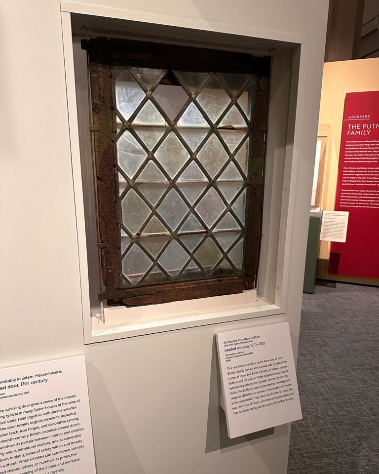 A 17th-century leaded glass window, attributed to Joshua Buffum, displayed at the Peabody Essex Museum in Salem, Massachusetts, alongside informational panels detailing its historical significance.